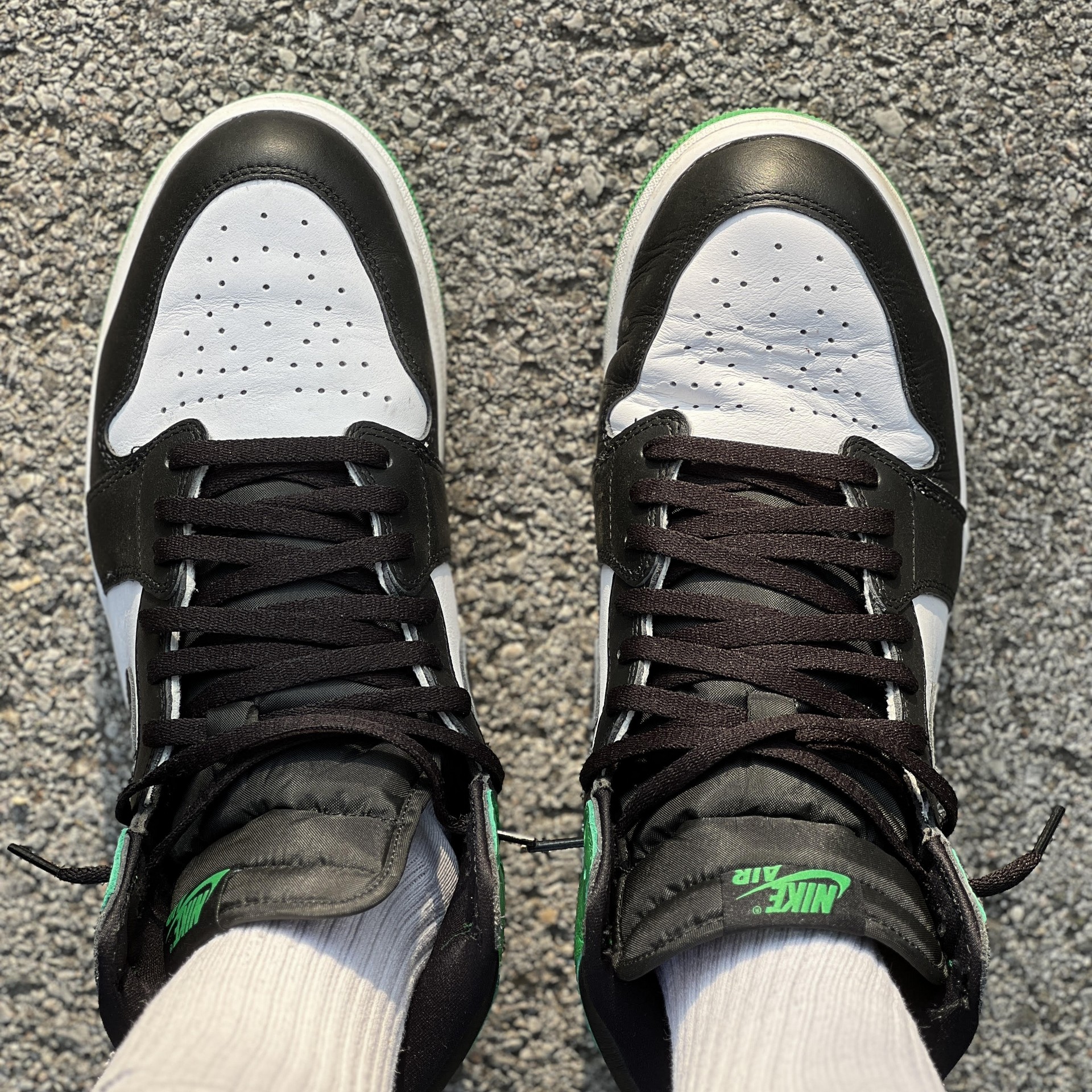 Black-and-grey Nike Air Jordan 1 high-top sneakers featuring a hidden crease protector, iconic retro basketball shoes with reinforced toe box.